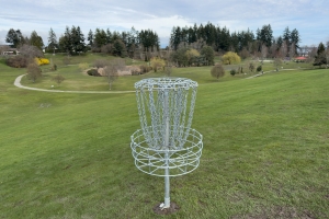 A new disc golf hole sits atop a hill at Diefenbaker Park, overlooking the grassy field.
